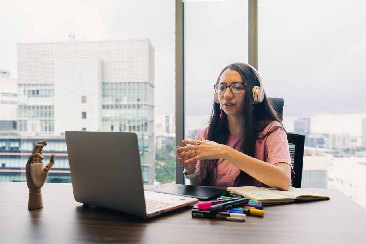 Woman wearing headphones discussing a project over a laptop video call
