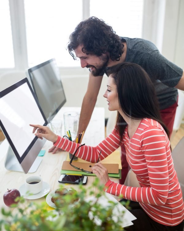 Male and female graphic designers interacting over computer in office